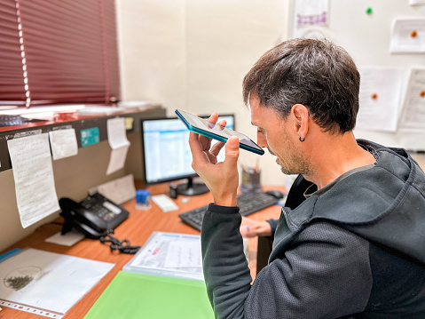 Deaf man with hearing aid listening to a voicemail message with mobile phone