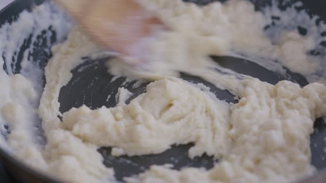 Woman making béchamel sauce from scratch with adding milk