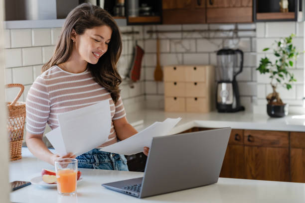 istock Young entrepreneur women working from home, looking at papers and using a notebook computer 1794985541