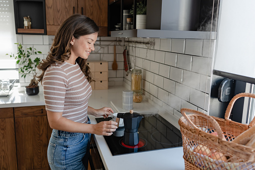 Beautiful young woman preparing coffee with a home espresso coffee maker