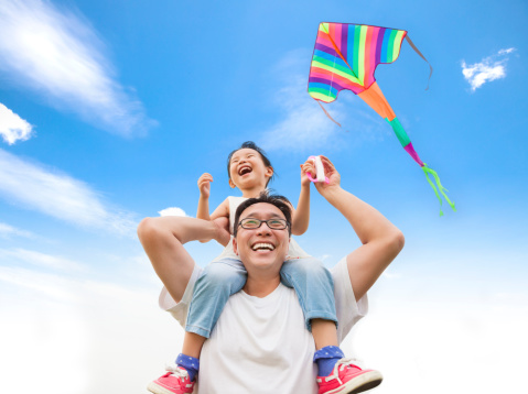Loving father and son having fun playing with flying kite on hiking adventure in nature