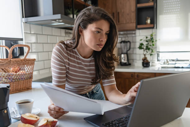 istock Young entrepreneur women working from home, looking at papers and using a notebook computer 1794986725