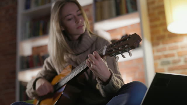 Teenage girl practicing playing guitar at home