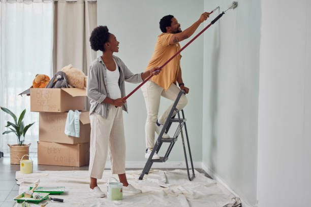 malerarbeiten, teamarbeit oder renovierung des hauses für schwarze paare, heimwerken oder umbau des hauses zusammen mit pinsel oder rolle. glückliches lächeln, frau und afrikanischer mann lieben es, mit partnerschaft oder zusammenarbeit an der wand zu a - heimwerken stock-fotos und bilder