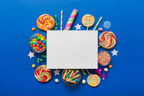 flat lay holiday composition. paper blank, lollipop, birthday decorations on colored background. top view, copy space for text - flavored ice variation birthday candy imagens e fotografias de stock