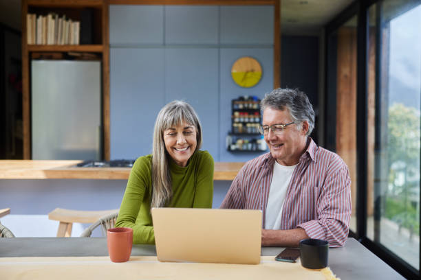 istock Smiling mature couple using a laptop together at a table at home 1795007568