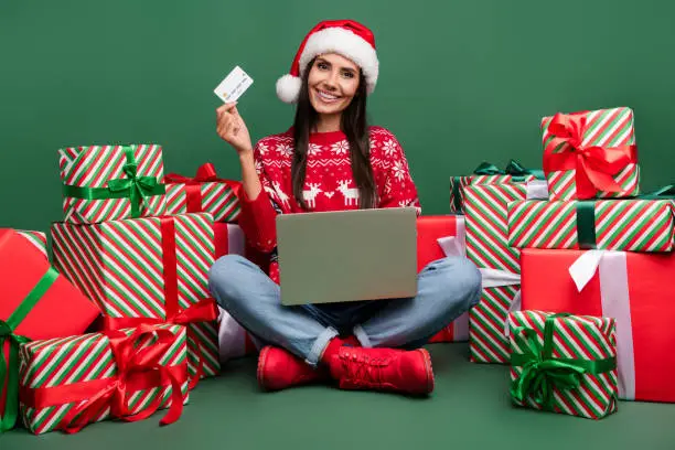 Full body photo of cute lady sit floor feast happy new year 2024 pay cashless laptop ecard many gifts isolated on green color background.