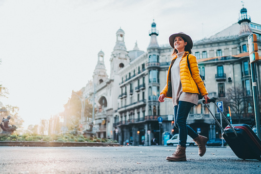 Woman with suitcase walking at the street in Barcelona