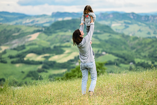 mother lift up child with beautiful mountain view