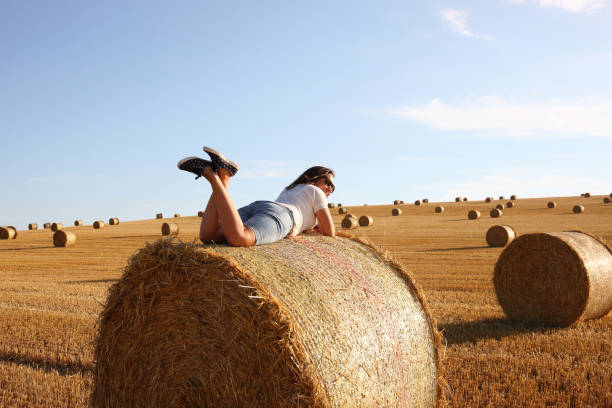 Young lady amongst haybales awaiting sunset