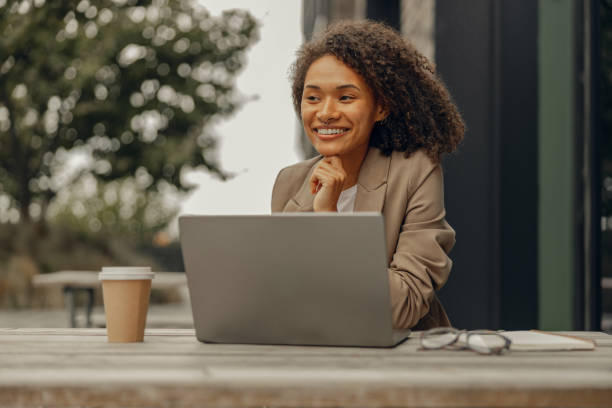 istock Smiling female freelancer working on laptop while sitting in cafe terrace. Distance work concept 1795063636