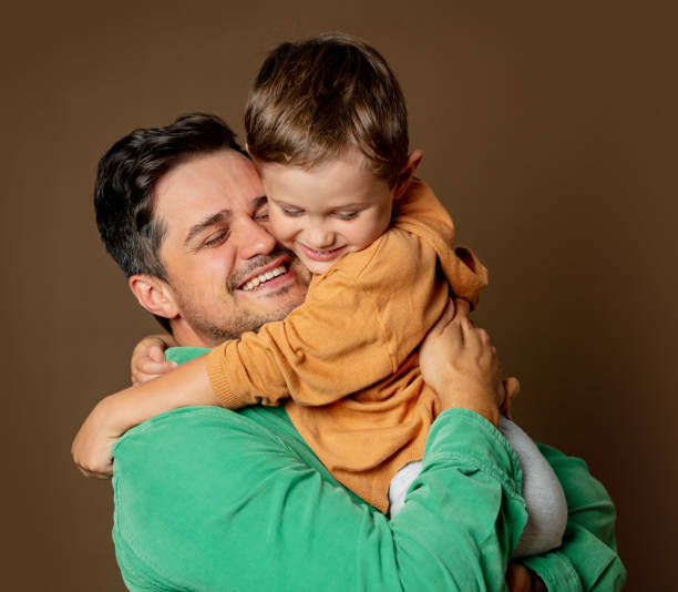 istock father and son cheerfully hugging on a brown background 1795068461