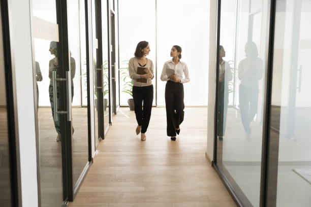 two multiethnic office employees women walking on hallway - couple walking old middle imagens e fotografias de stock