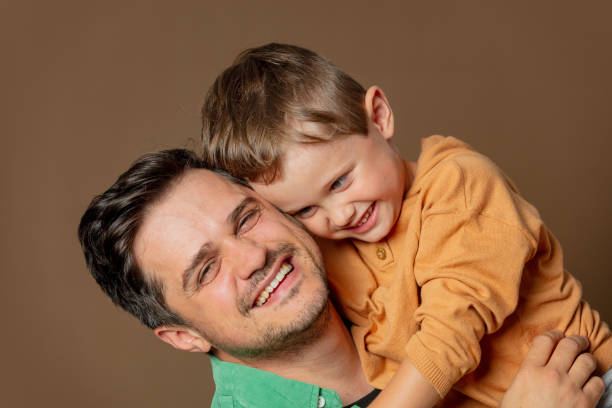 istock father and son cheerfully hugging on a brown background 1795068510