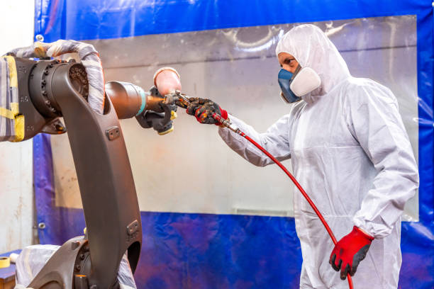 istock Industrial painter using spray gun to paint a robotic arm 1795083906