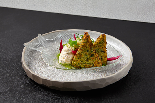 Zucchini fritters with fish ceviche and cheese cream. Healthy food - vegetables fritters and fish tartar. Inspirational chefs food on dark background. Modern food. Contemporary menu for restaurant