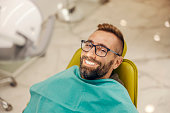 Portrait of a patient sitting at dentist office in chair with perfect smile.