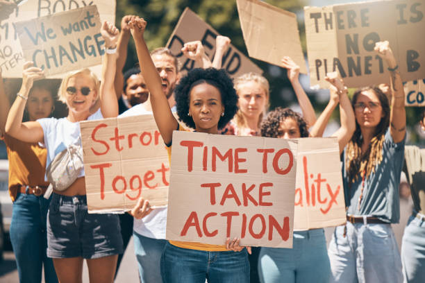 protesta, huelga y cambio climático con un grupo de mujeres que luchan por nuestro planeta o los derechos humanos en la ciudad. medio ambiente, movimiento y contaminación con una activista que marcha contra el calentamiento global - black sign holding vertical fotografías e imágenes de stock