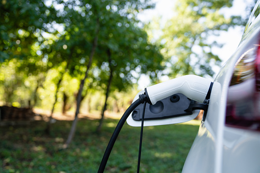 Close up of electric car inlet with a connected charging cable.