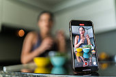 Close-up of a mobile phone recording a young woman vlog preparing salad in kitchen at home