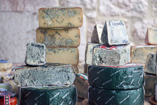 Indulge in the richness of Asturian culture with 'Typical Asturian Blue Cheese Counter at an Artisan Products Market.' This evocative image showcases the artisanal allure of Asturian cheese, labeled 'Reserve' and 'Three Milks,' signifying a blend of cow, goat, and sheep milk. A sensory journey through regional flavors at the heart of an authentic market experience.
