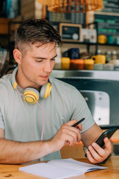 Stylish male studen sits at table in a cafe with mobile phone stock photo