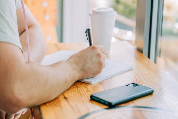 istock Stylish male studen sits at table in a cafe with pen and notebook 1795109500