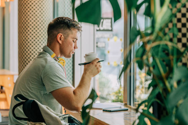 istock Stylish male studen sits at table in a cafe with pen and notebook 1795110031