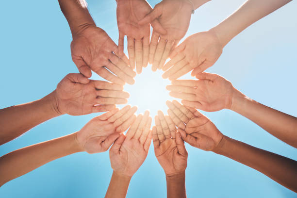 istock Hands in circle together, blue sky and sun, diversity and community in collaboration for support and success. Teamwork, hands together and summer sunshine, positive vision and trust between friends. 1795118169
