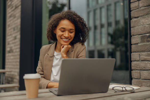 istock Smiling female freelancer working on laptop while sitting in cafe terrace. Distance work concept 1795119773