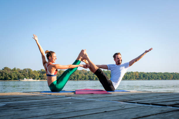 istock Couple practicing yoga on wooden deck by the river 1795135306