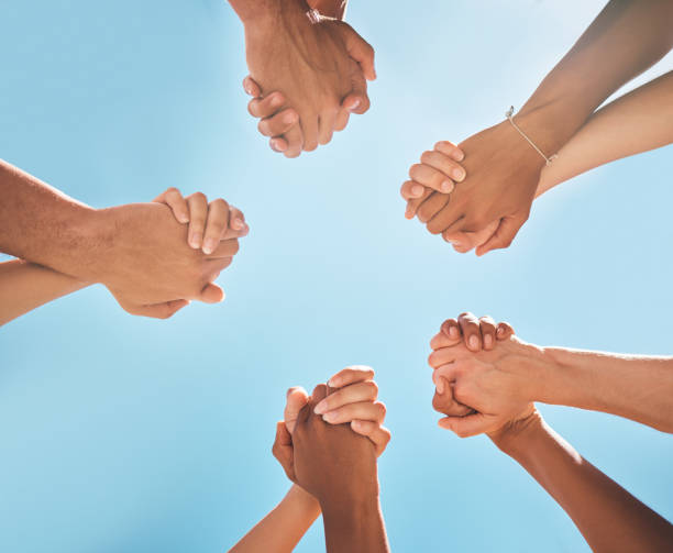 istock Hands, solidarity and holding hands, support and collaboration, partnership and diversity with blue sky background. Teamwork, unity and group of people, team building and community with trust. 1795138600