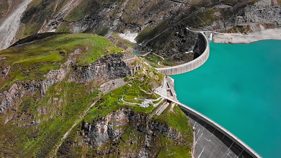 Hydroelectric dam and reservoir lake in French Alps mountains. Renewable energy and sustainable development with hydropower generation. Aerial view.