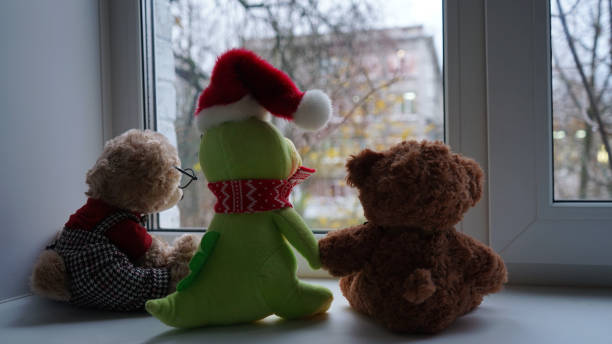 Green plush dragon and bears look at window.