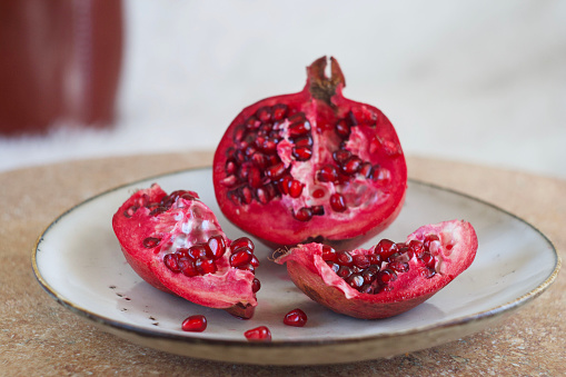 Pomegranate lies in a plate on a round table