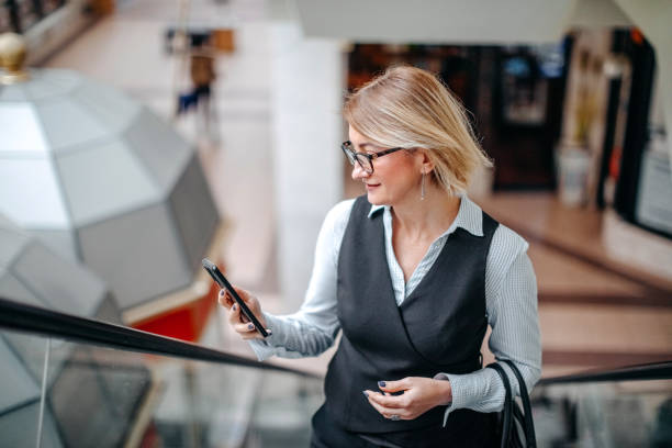 istock Woman on a break using mobile phone for on line shopping while moving up with elevated stairs 1795148880