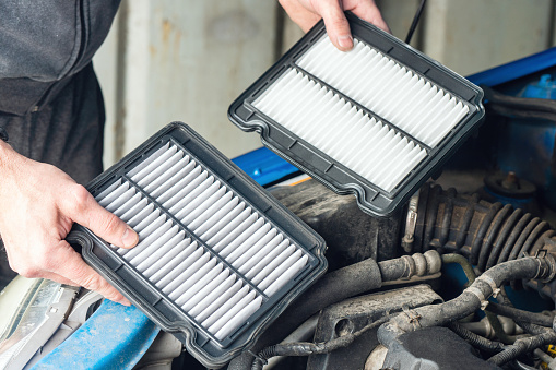 A mechanic replaces the air filter in a car.