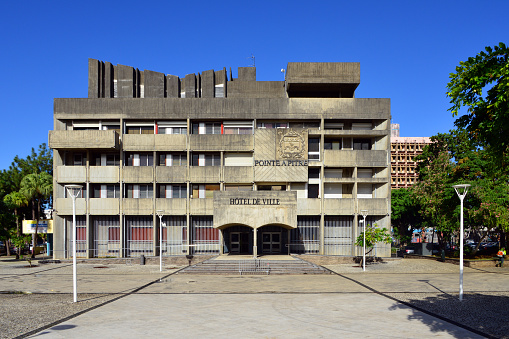 Pointe-à-Pitre (Antillean Creole: Pwentapit, or simply Lapwent), Guadeloupe: concrete façade of Pointe-à-Pitre City Hall - architects Raymond Creveaux and Jacques Tessier, Boulevard Faidherbe / Martyrs-de-la-Liberté square. Mairie of PaP commune. Since 2007, Pointe-à-Pitre has been the only sub-prefecture of Guadeloupe; it is the capital of the district of Pointe-à-Pitre and the economic capital of Guadeloupe.