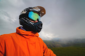Portrait of a man in a protective sports helmet and reflective glasses. An athlete in full face in the mountains looks to the side