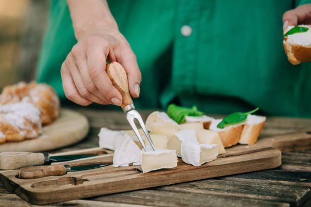 Stylish woman in green shirt stabs cheese snack with a fork stock photo