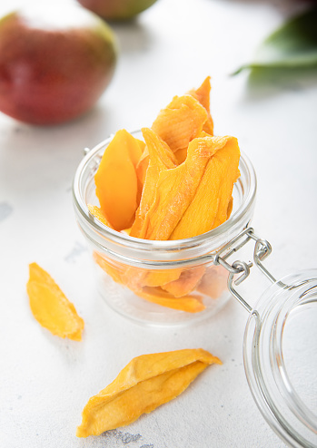 Sweet dried mango slices with fresh raw fruits on light background.Top view.