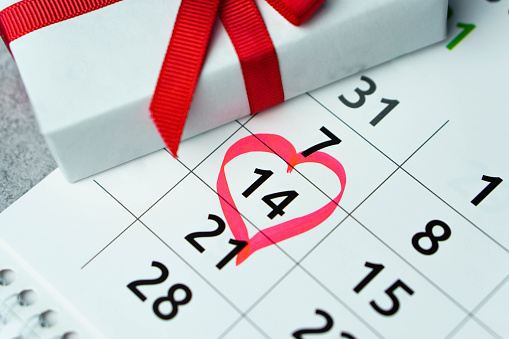 Close up calendar with 14 February date Valentines day with red heart shape marker and gift box