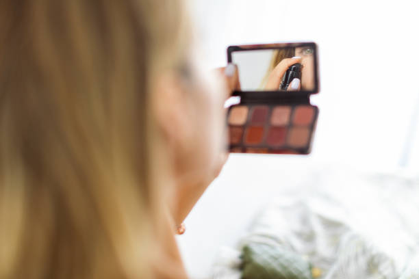 Woman wearing on makeup in front of the mirror at bedroom