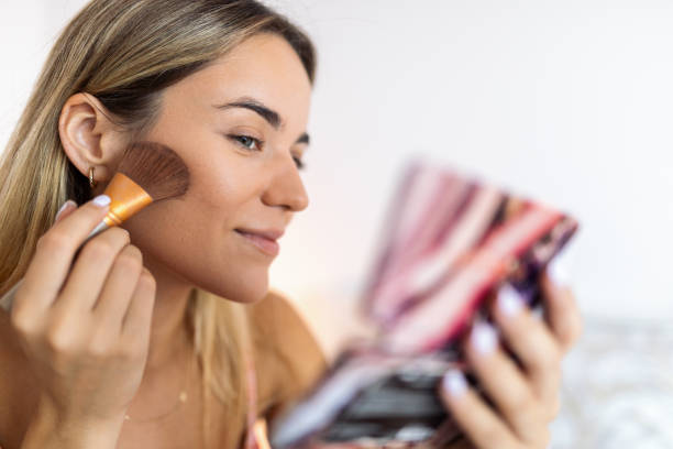 Young woman putting on makeup
