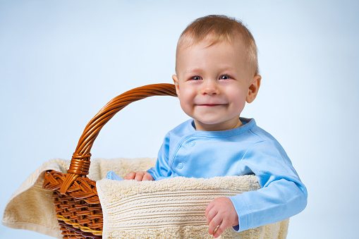 Eight month baby sitting in basket and smiling on white and blue background