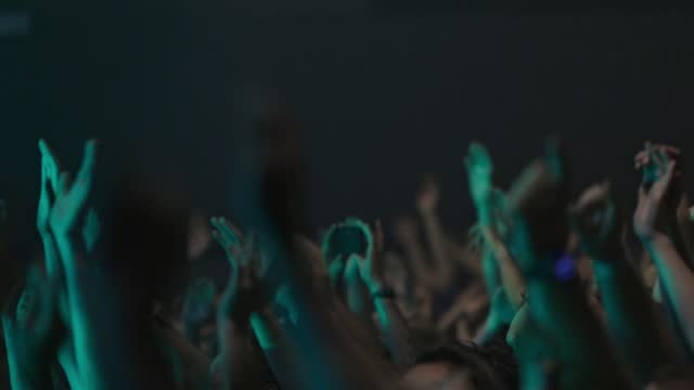 Hands of fans of a punk band in a crowd in a small club