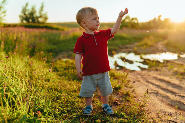 istock Two-year-old child standing in a field with his hand up 1795266051