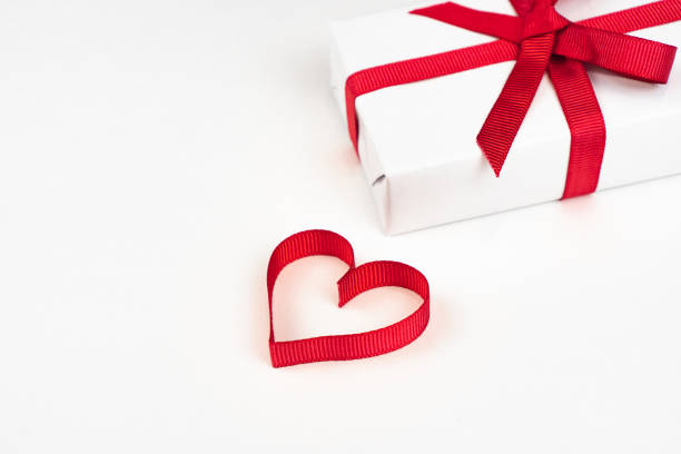 istock White boxes with red ribbons and decorative heart isolated on white background. Greeting card 1795268288