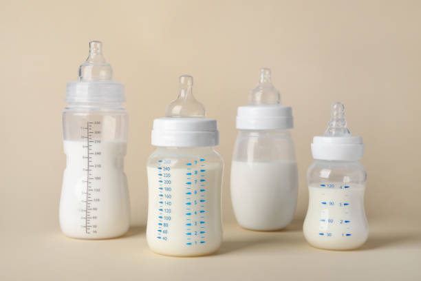 Feeding bottles with baby formula on beige background