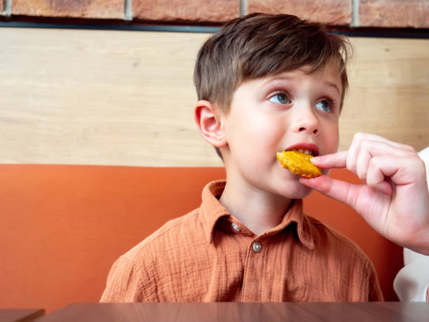 istock Little toddler boy eating nuggets indoor 1795280374